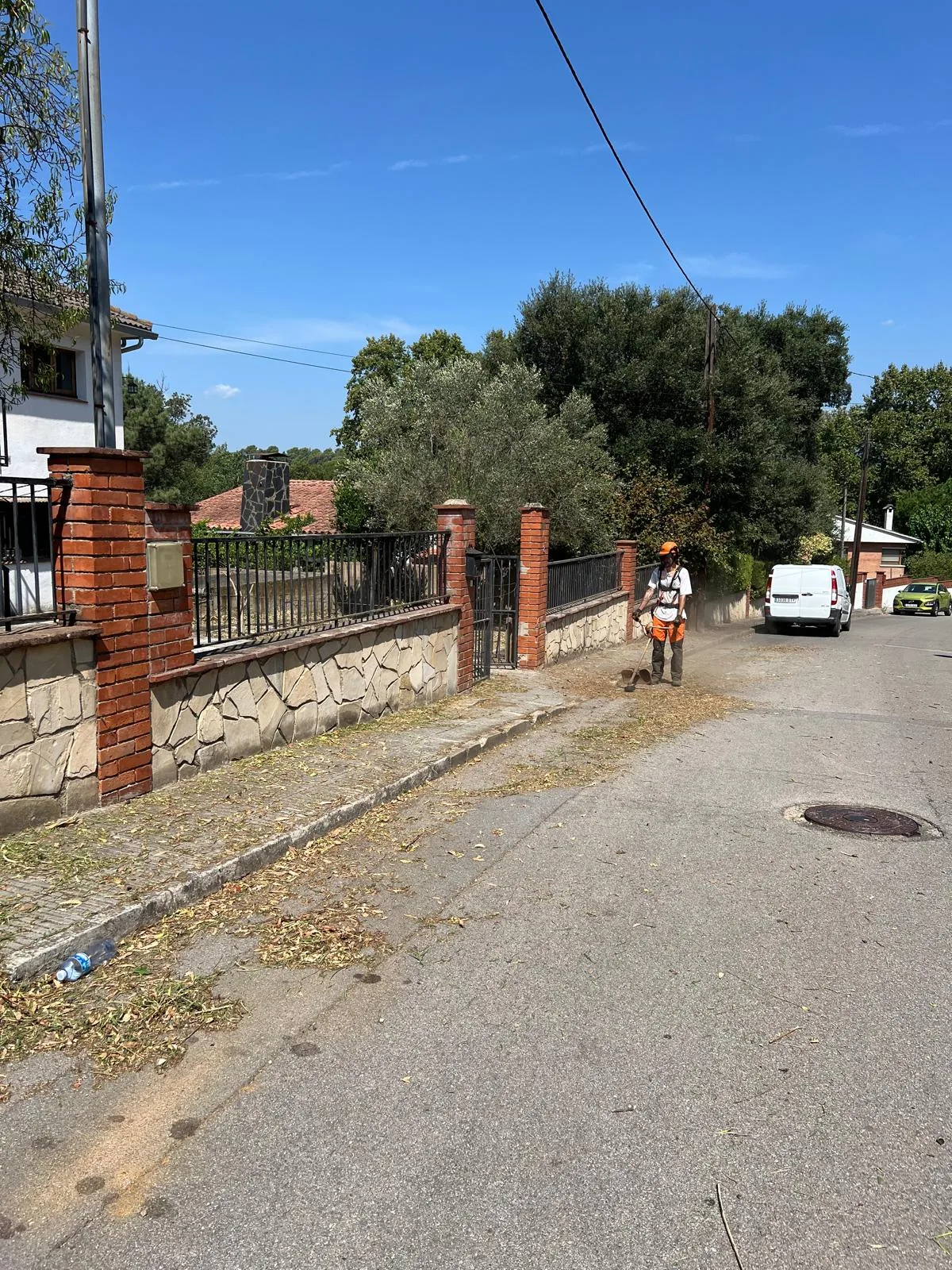 Operario limpiando con soplador la acera y la calle de acceso a la finca de Can Coll tras el desbroce