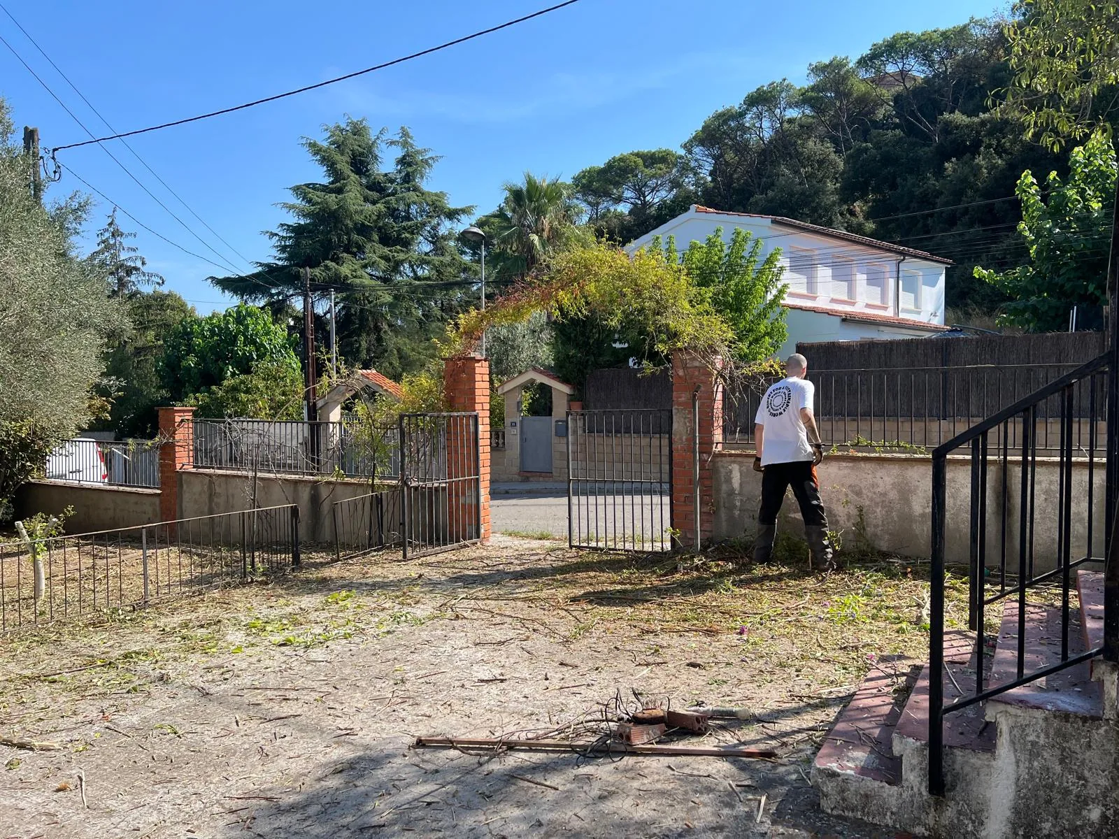 Operario recogiendo los últimos restos en la entrada de la finca de Can Coll, ya desbrozada y despejada
